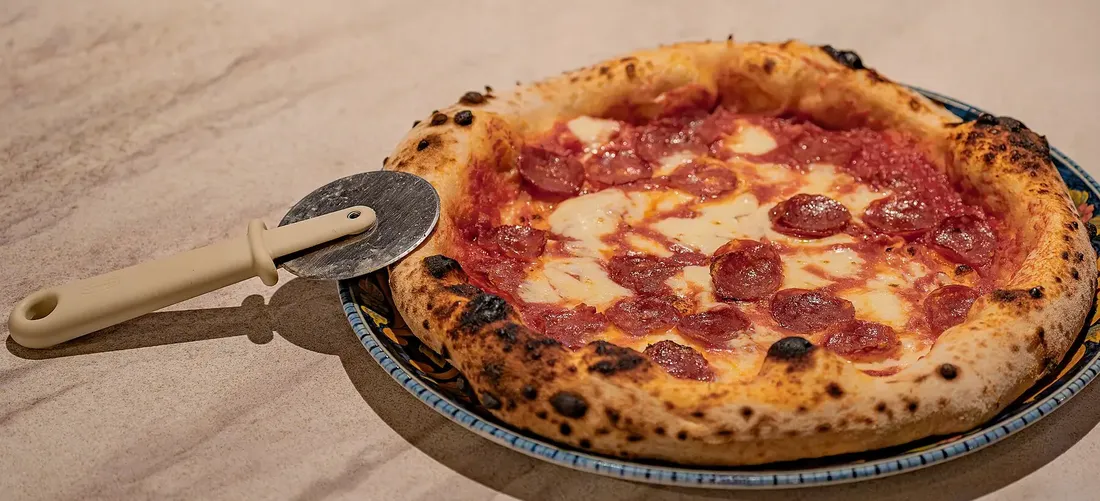 En nybakad pizza med salami på ett fat